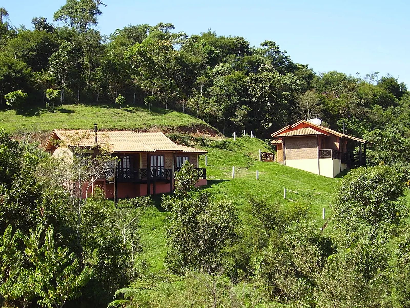 Dois chalés na encosta, cercados de mata e gramado