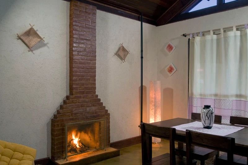 Lareira de tijolos acesa ao lado da mesa de jantar de madeira