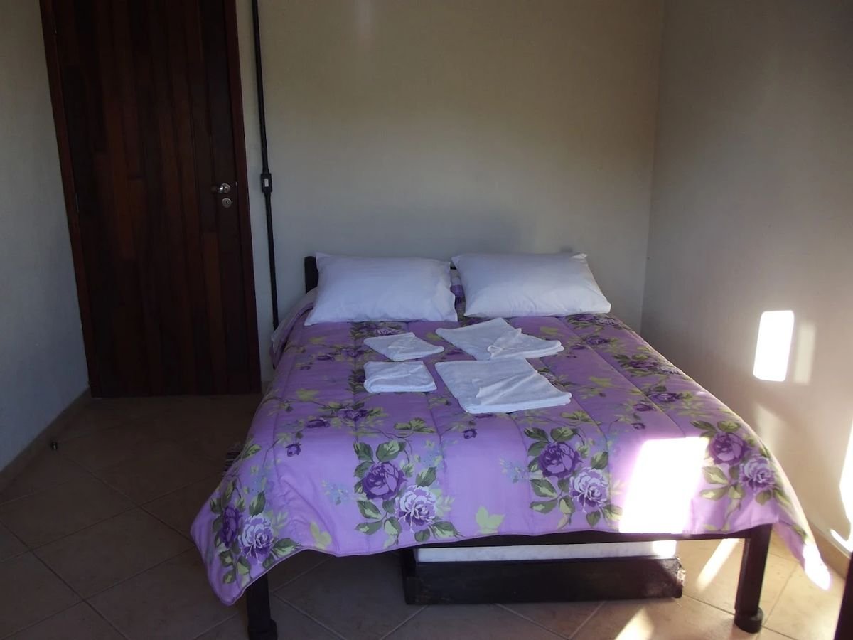 Cama de casal arrumada com toalhas, luz do sol entrando pela janela
